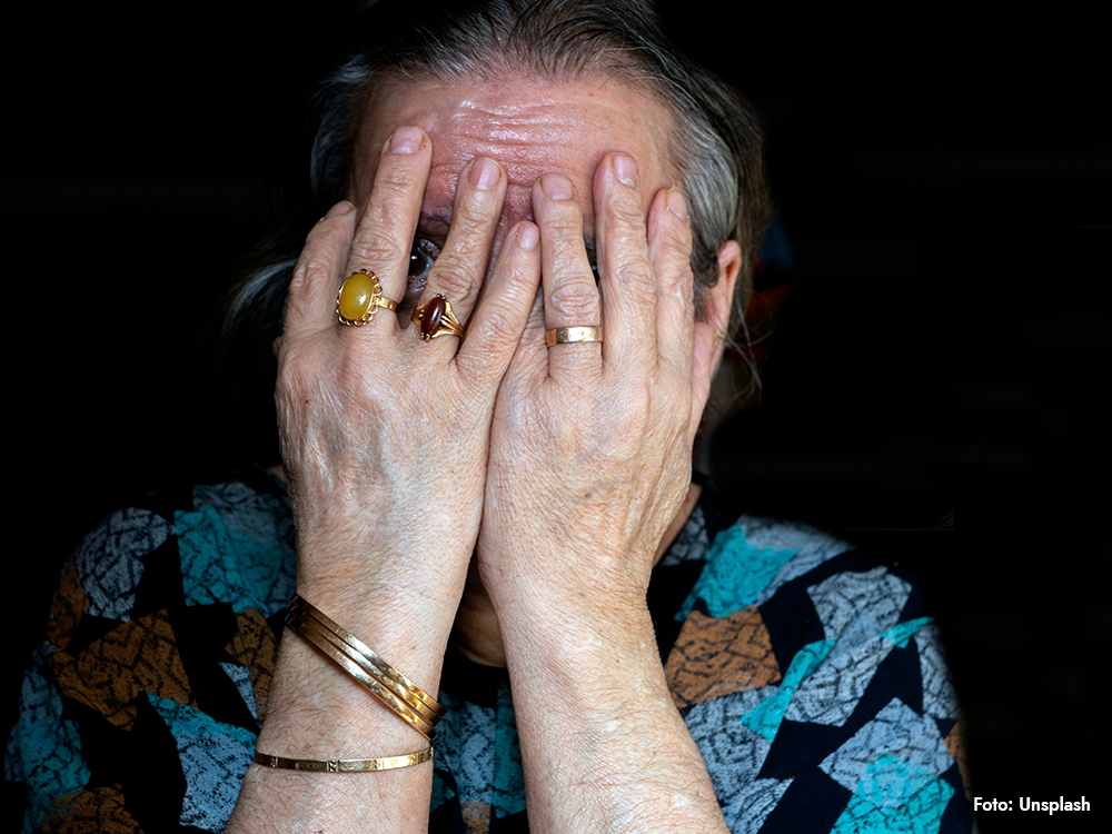 Äldre kvinna med händerna för ansiktet, kopplat till måndagsångest, höga kortisolnivåer, stress och hjärtproblem.