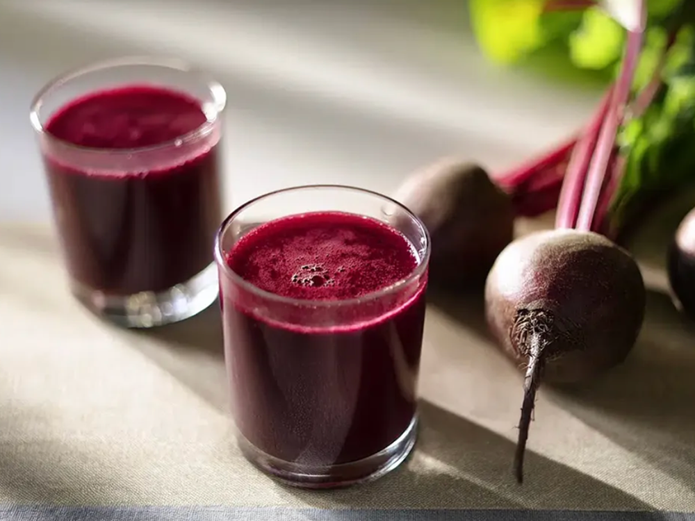 Vad är rödbetsjuice bra för? Två shots med rödbetsjuice står på ett bord bredvid några rödbetor.