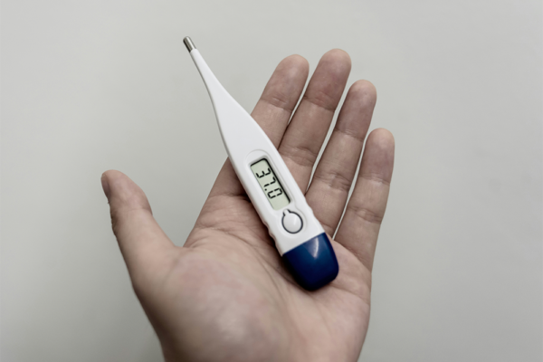 Bästa febertermometern – digital febertermometer i handen som visar temperatur på displayen.