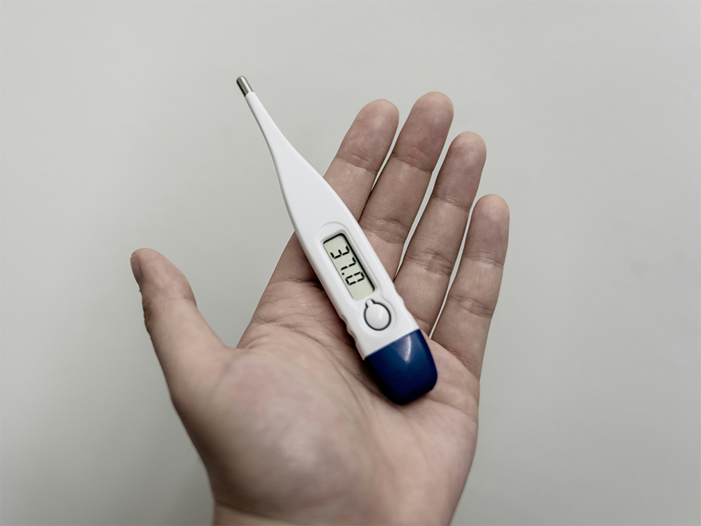 Bästa febertermometern – digital febertermometer i handen som visar temperatur på displayen.