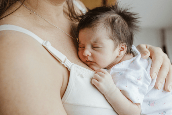 Bästa bröstpumpen 2026: mamma med sovande nyfödd