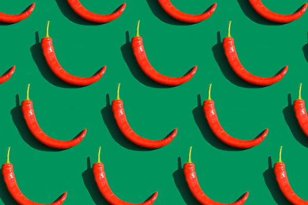 Röda chilipeppar mot grön bakgrund, som illustration till artikel om kryddor och kronisk inflammation.