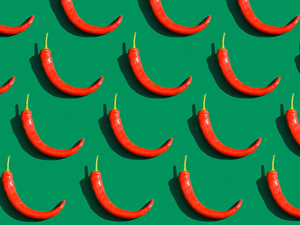 Röda chilipeppar mot grön bakgrund, som illustration till artikel om kryddor och kronisk inflammation.