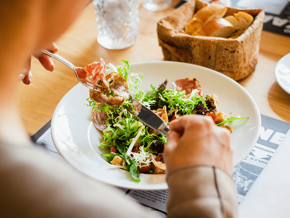 Startsida 17 Person äter sallad med kött i en artikel om protein och åldrande.