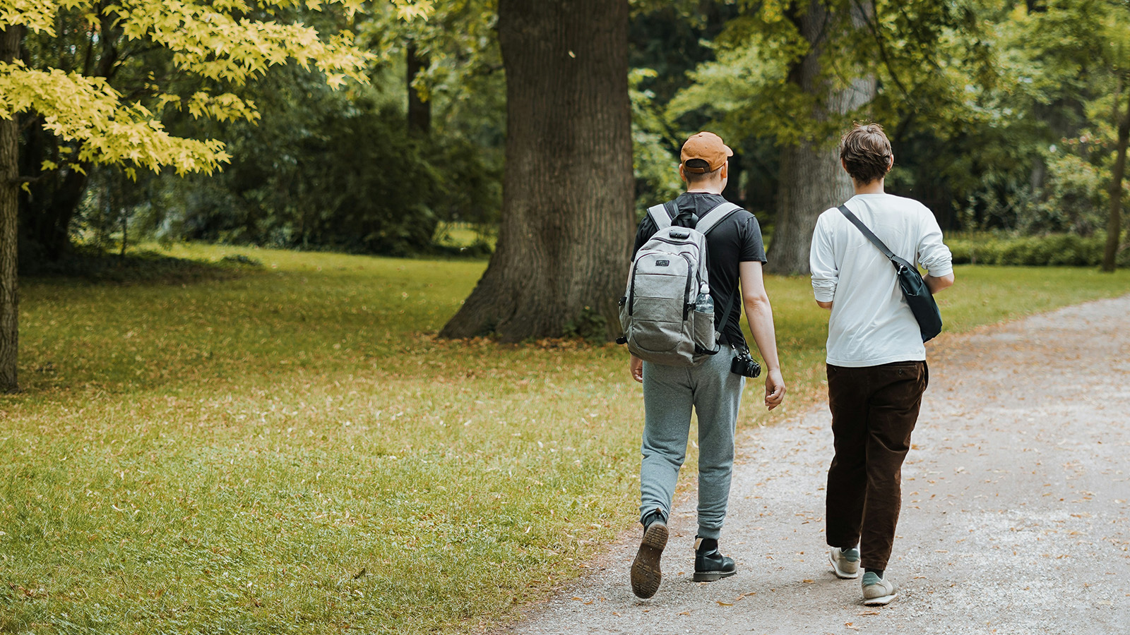Två yngre vuxna promenerar i en park – studie undersöker cancer hos yngre och biologiskt åldrande.