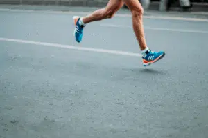 Vad är fysisk aktivitet? Här syns benen på en person i shorts som springer på asfalt – ett exempel på motion.
