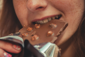 Kvinna med långt brunt hår äter choklad, en av flera populära sötsaker