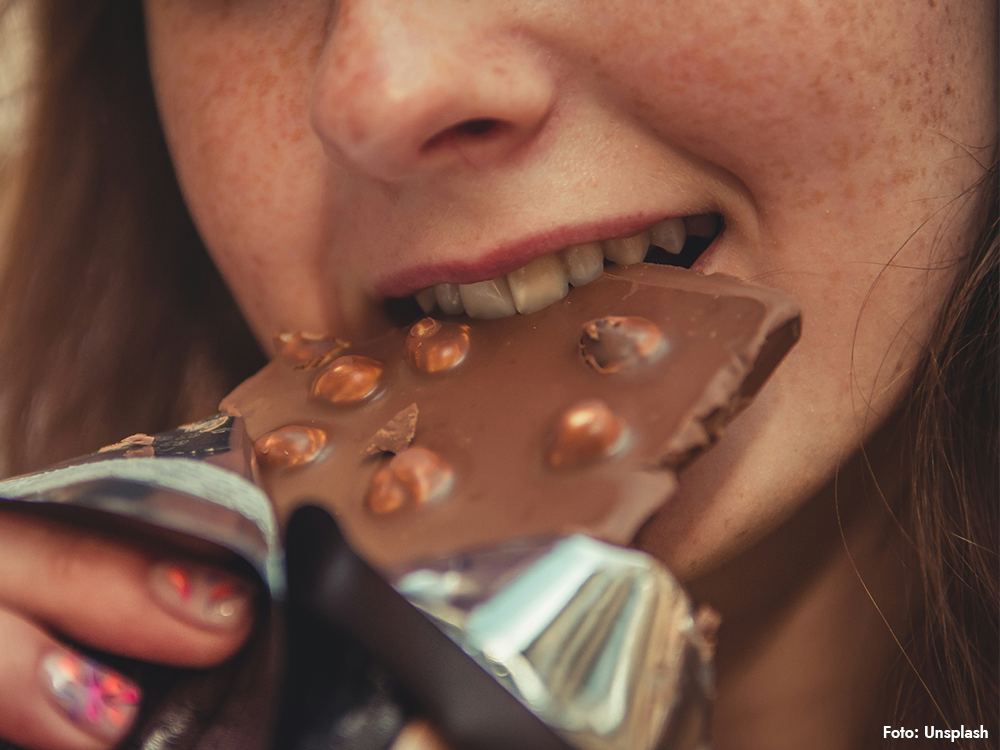 Kvinna med långt brunt hår äter choklad, en av flera populära sötsaker