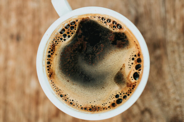 En kopp svart kaffe på träbord, illustration till artikel om kaffe och förmaksflimmer, hjärtflimmer och kaffekonsumtion i Sverige.