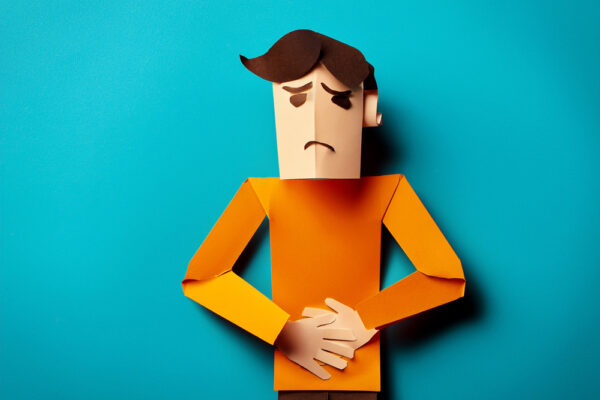 Illustration av person med magont och förstoppning – pappersfigur som håller sig om magen, bild till artikel om kronisk förstoppning, kost vid förstoppning, medelhavskost och växtbaserad kost.