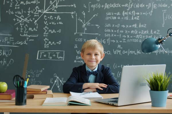 Pojke i klassrum framför mattetavla med formler, bild för särskilt begåvade barn och talangutveckling.